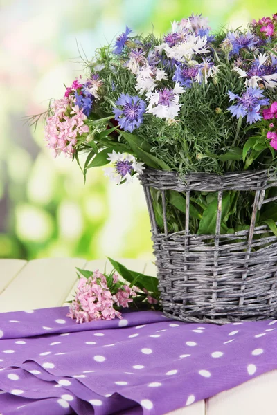 Beautiful bouquet in basket on wooden table on natural background — Stock Photo, Image