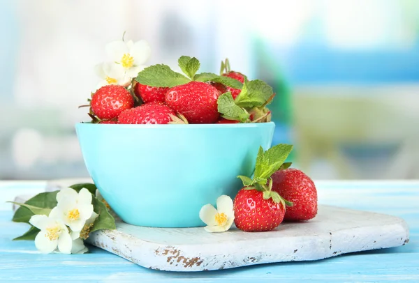 Fresas dulces maduras en tazón sobre mesa de madera azul —  Fotos de Stock