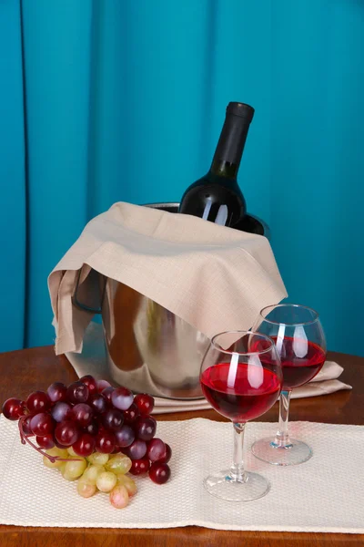 Vino e bicchieri su tavola rotonda su sfondo stoffa — Foto Stock