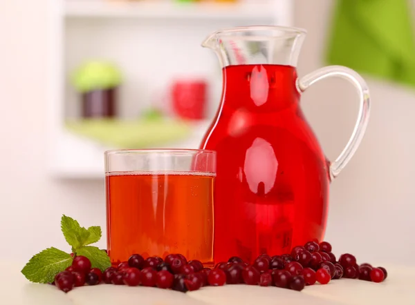 Werper en glas cranberry sap met rode veenbessen op tafel — Stockfoto