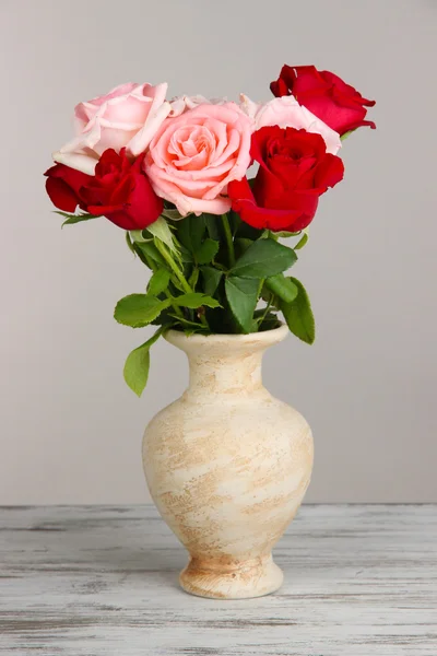 Beautiful bouquet of roses in vase on table on gray background — Stock Photo, Image