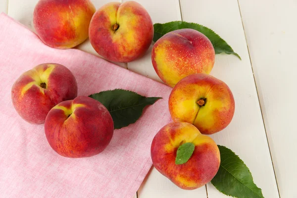 Peaches on napkin on wooden table — Stock Photo, Image