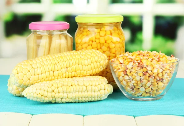 Fresh, canned and dried corn on wooden table, on bright background — Stock Photo, Image