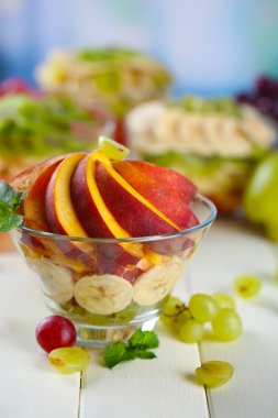 Beyaz ahşap masa üzerinde cam kase lezzetli meyve salatası