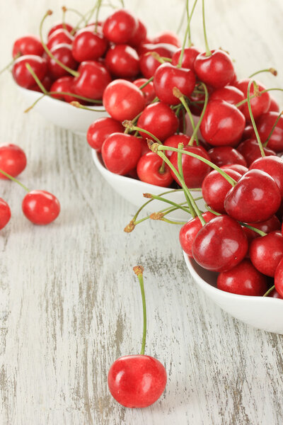 Cherry berries in bowl on wooden table close up