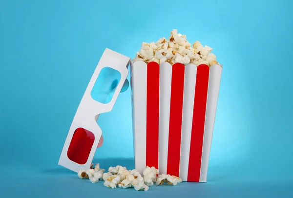 Palomitas de maíz y gafas 3D sobre fondo azul — Foto de Stock