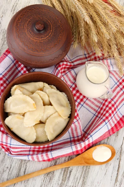 Tasty dumplings with fried onion on brown plate, on wooden background — Stock Photo, Image