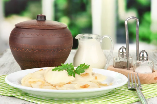 Tasty dumplings with fried onion on white plate, on bright background — Stock Photo, Image