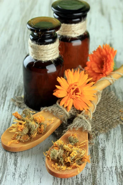 Frascos de medicina y flores de caléndula sobre fondo de madera —  Fotos de Stock