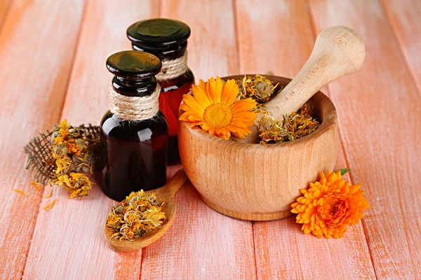 Medicine bottles and calendula flowers on wooden background — Stock Photo, Image