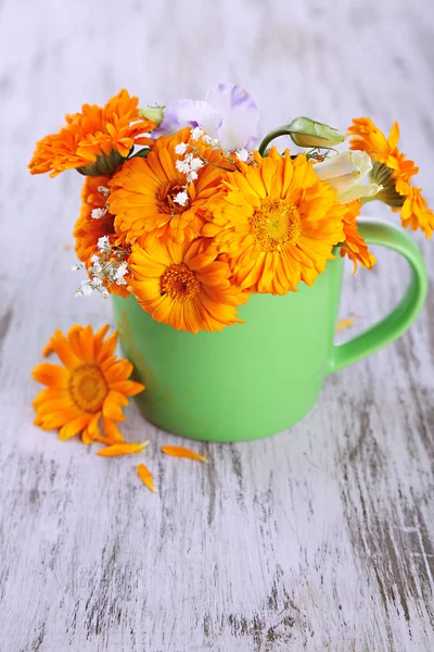 Calendula bloemen in cup op houten achtergrond — Stockfoto