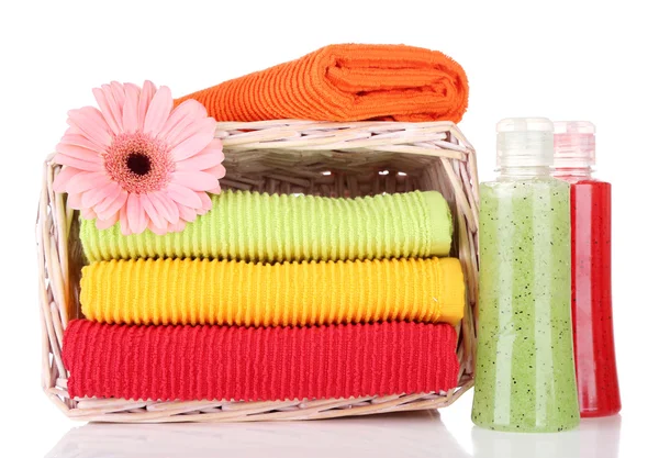 Toalhas coloridas em cesta e garrafas de cosméticos isoladas em branco — Fotografia de Stock