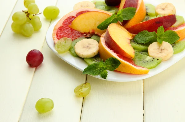 Assortimento di frutta a fette su piatto, su tavolo di legno bianco — Foto Stock