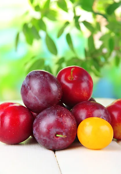 Ripe plums on wooden table on natural background — Stock Photo, Image