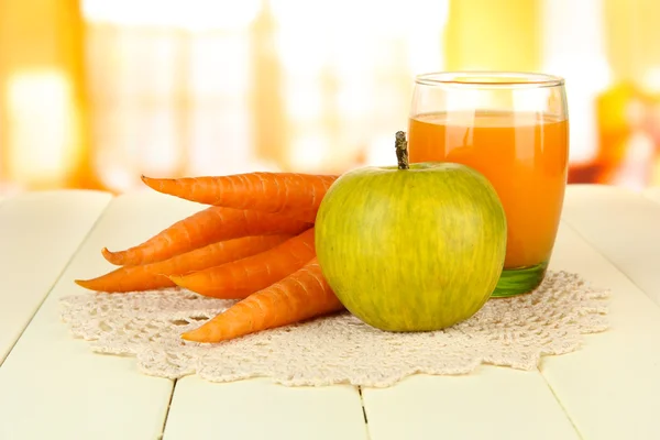 Tas de carottes et pomme verte, verre de jus, sur la table en bois de couleur sur fond lumineux — Photo