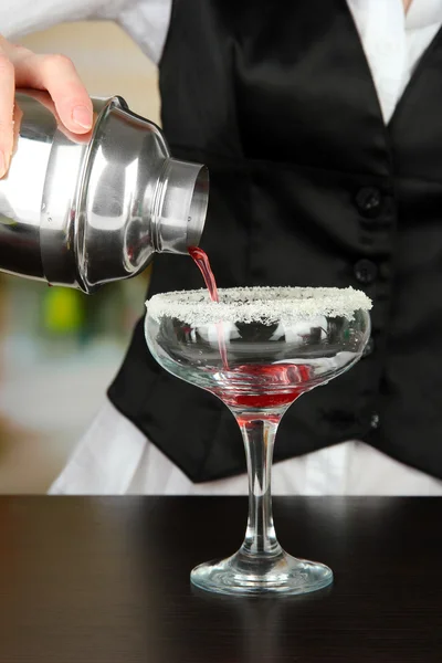 Бармен рука с шейкером наливая коктейль в стекло, на ярком фоне — стоковое фото