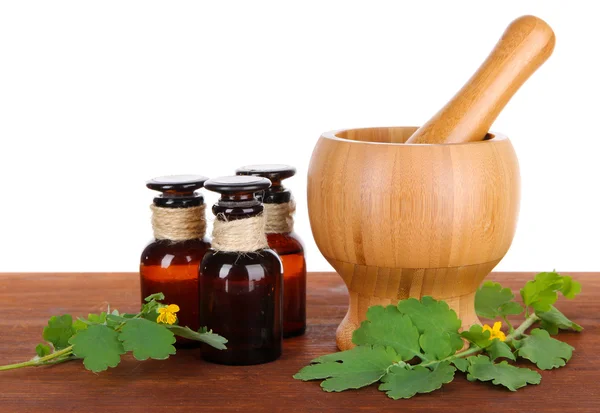 Celidonia floreciente con frascos de medicamentos en la mesa sobre fondo blanco — Foto de Stock