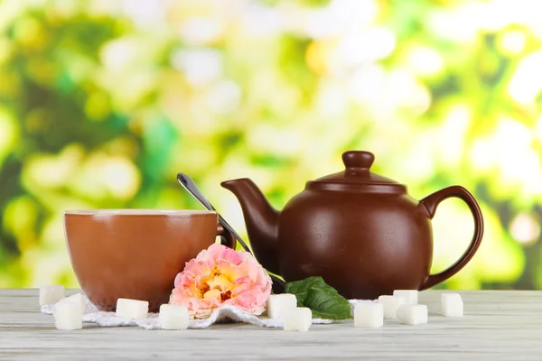 Wasserkocher und Tasse Tee aus Teerose an Bord auf Serviette auf Holztisch auf Naturhintergrund — Stockfoto