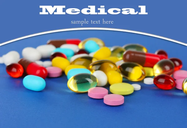 Surtido de pastillas, tabletas y cápsulas sobre fondo azul — Foto de Stock