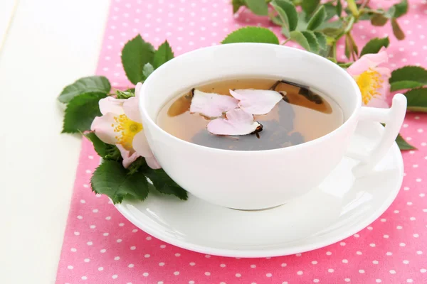 Чашка травяного чая с цветами тазобедренной розы на белом столе — стоковое фото