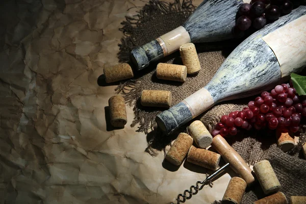 Vecchie bottiglie di vino, uva e tappi su sfondo di vecchia carta — Foto Stock