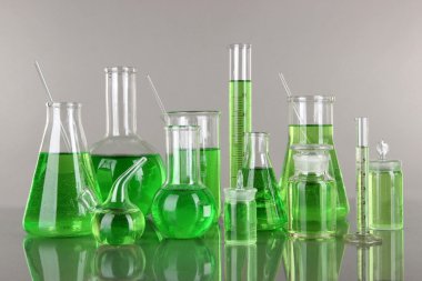 gri zemin üzerine yeşil sıvı ile test tüpleri