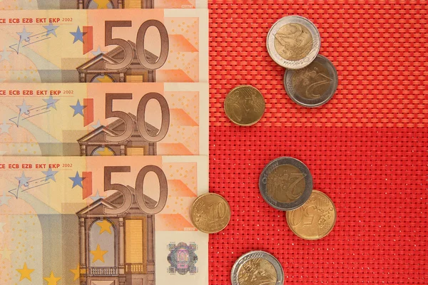 Euro banknotes and euro cents on red background — Stock Photo, Image