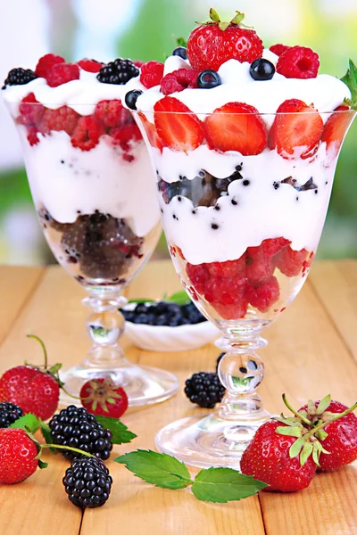 Naturjoghurt mit frischen Beeren auf Holztisch auf grünem Hintergrund — Stockfoto