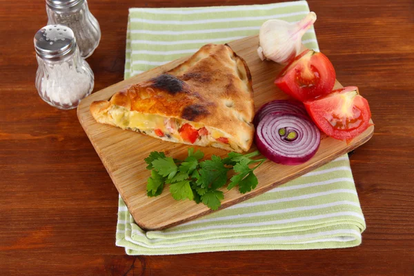 Pizza calzone trä ombord på servett på träbord — Stockfoto