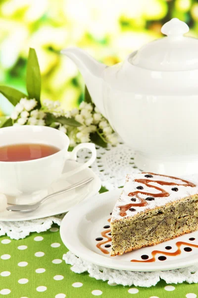 Delicioso pastel de semillas de amapola con taza de té en la mesa sobre fondo brillante —  Fotos de Stock