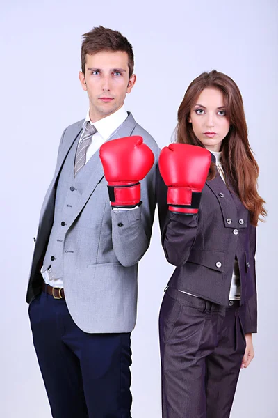 Young business in boxing gloves on grey background