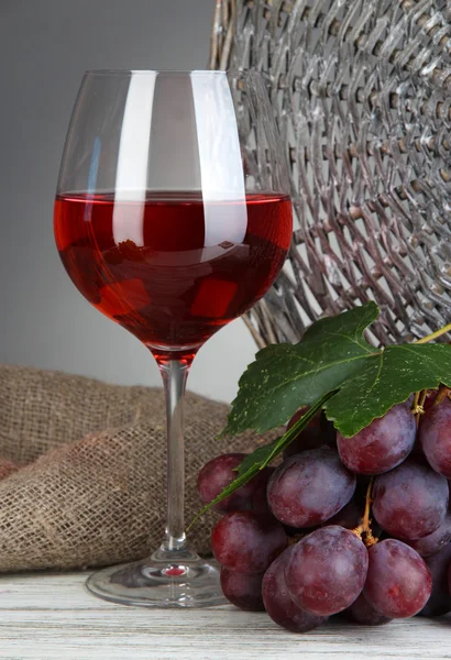 Rijp heerlijke druiven met glas wijn op tafel op grijze achtergrond — Stockfoto