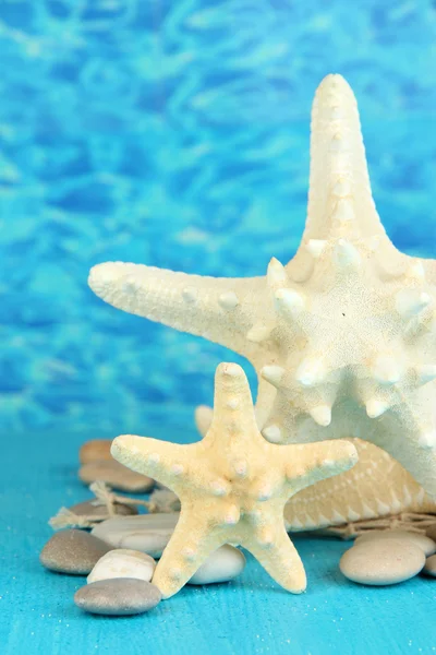 White starfishes on blue wooden table on sea background — Stock Photo, Image