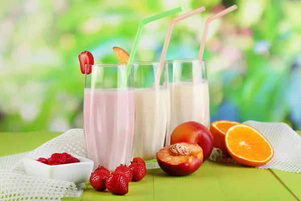 Deliciosos batidos de leche con fresas y melocotón sobre mesa de madera sobre fondo natural —  Fotos de Stock