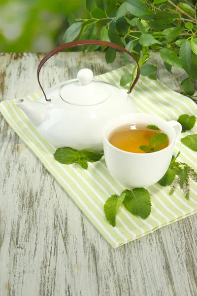 Czajnik i filiżanki herbaty ziołowej z mięty na drewnianym stole — Zdjęcie stockowe
