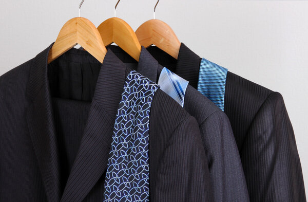 Suits and ties on hangers on gray background