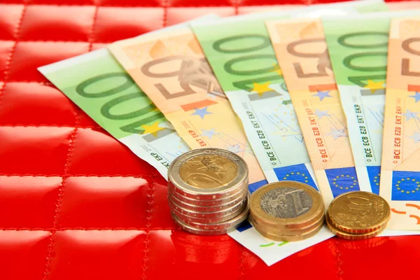 Euro banknotes and euro cents on red background — Stock Photo, Image