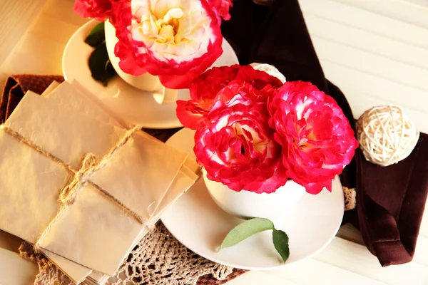 Roses in cups on napkins on wooden background — Stock Photo, Image