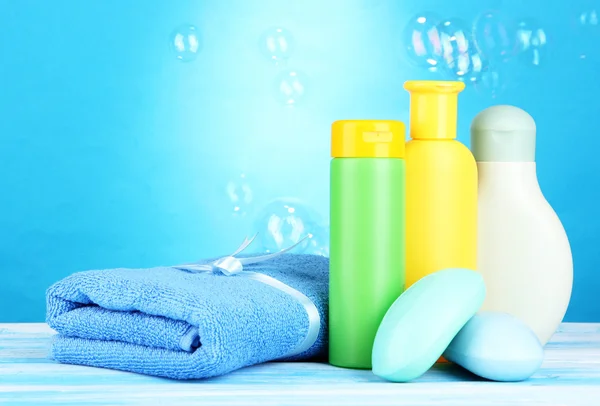 Cosmetici per bambini, asciugamani e sapone su tavolo di legno, su sfondo blu — Foto Stock