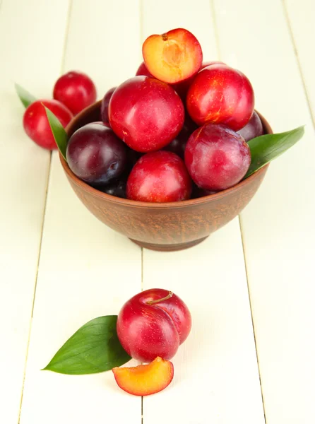 Ripe plums in bowl on wooden table close-up — Stock Photo, Image