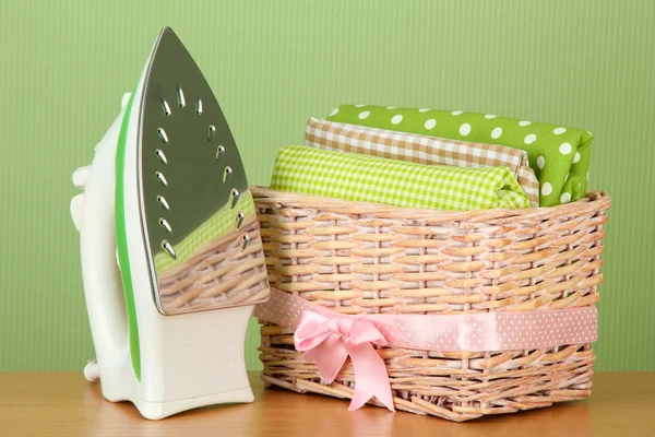 Steam iron and wicker basket with clothes, on color background — Stock Photo, Image