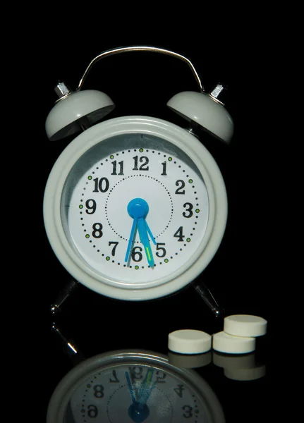 Relógio de alarme de estilo antigo e pílulas, isolado em preto — Fotografia de Stock