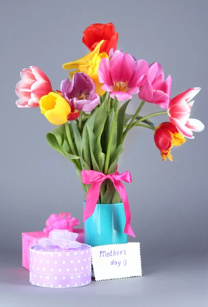 Mooie tulpen in boeket met giften en nota over grijze achtergrond — Stockfoto