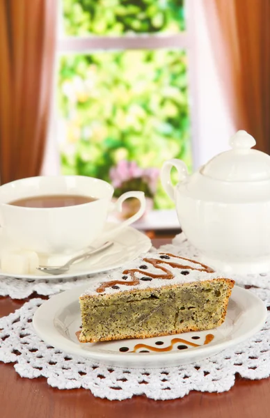 Delicious poppy seed cake with cup of tea on table in room — Stock Photo, Image