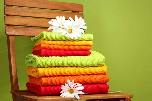 Toallas y flores en silla de madera sobre fondo verde — Foto de Stock