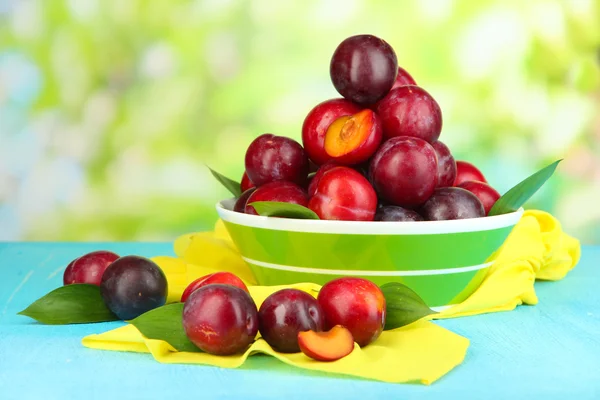 Mogna plommon i skål på träbord på naturliga bakgrund — Stockfoto