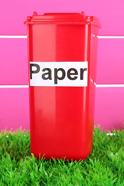 Recycling bin on grass on pink background — Stock Photo, Image