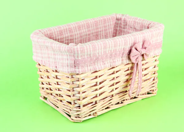 Wicket basket with pink fabric and bow, on color background — Stock Photo, Image