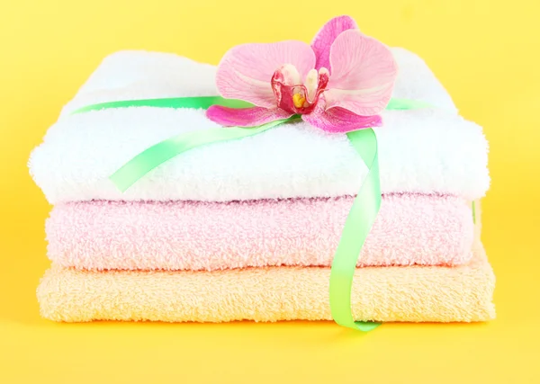 Towels tied with ribbon on yellow background — Stock Photo, Image