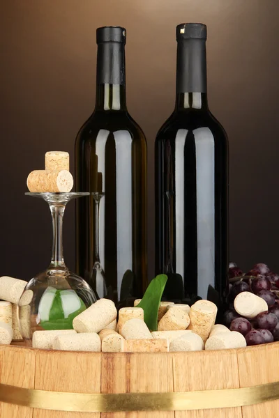 Wine and corks on barrel on brown background — Stock Photo, Image